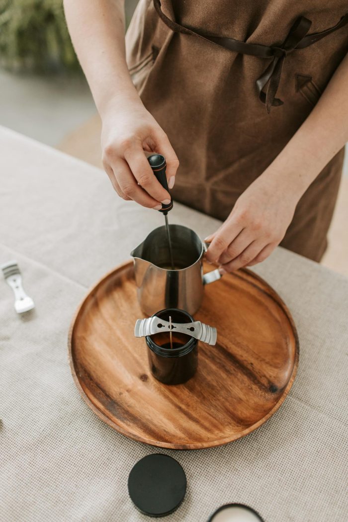 Photo by Vlada Karpovich Close-up of a person making candles with metal cup and tools on a wooden tray.