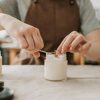 Close-up of artisan crafting handmade candles with wooden wicks in workshop.