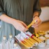 Craftsman packing rolled candles with bottles and jars on display.