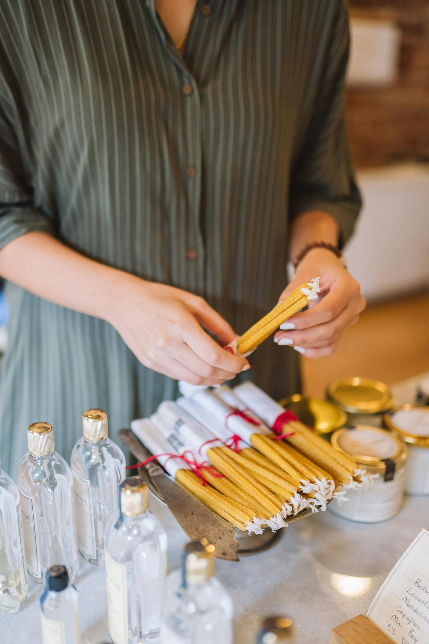 Craftsman packing rolled candles with bottles and jars on display.